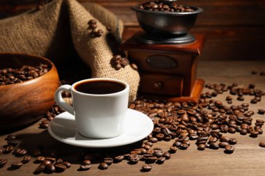 Kahve fincanda, fasulye ve öğütücü ahşap masada.