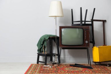 Retro TV tribünde, siyah sandalye, bavul ve lamba beyaz duvarın yanında, mesaj için yer var. Kullanılmış eşyalar