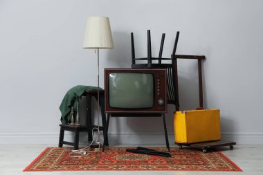 Retro TV kürsüde, siyah sandalye, bavul ve lamba açık gri duvarın yanında. Kullanılmış eşyalar