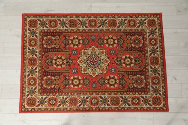 Hafif ahşap zeminde desenli yumuşak kırmızı halı, üst manzara. Kullanılmış eşyalar