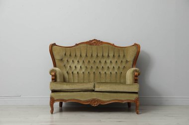 Açık gri duvarın yanındaki eski moda kanepe. Kullanılmış eşyalar