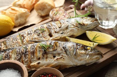 Ahşap masada, ekmek, biberiye ve limonla servis edilen lezzetli kavrulmuş deniz kabuğu balığı. Ev yapımı deniz ürünleri yemeği.