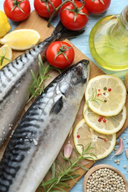 Taze çiğ uskumrular ve baharatlar açık mavi ahşap masada, düz yerde. Deniz ürünleri lezzetleri.