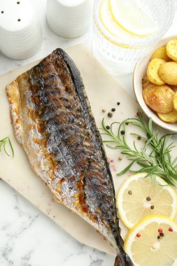 Beyaz mermer masada baharat ve patatesle servis edilen kızarmış uskumru. Ev yapımı deniz ürünleri yemeği.