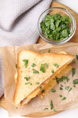 Eritilmiş peynirli lezzetli sandviç ve beyaz masada maydanoz.