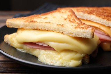 Eritilmiş peynirli ve ahşap masada jambonlu lezzetli sandviçler.