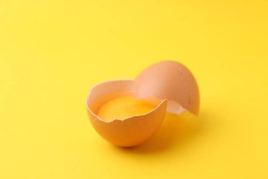 Sarı arka planda kırılmış bir tavuk yumurtası, yakın plan.