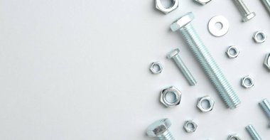 Beyaz arka planda metal cıvatalar ve fındıklar, düz yatış. Metin için boşluk