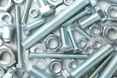 Beyaz arka planda metal cıvatalar ve fındıklar, düz yatış