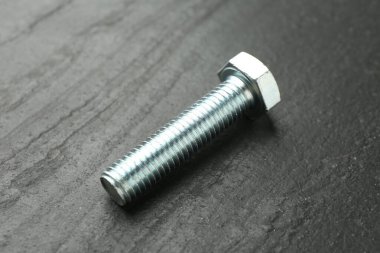 Bir metal cıvata siyah masada, yakın plan.