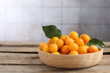 Olgun sarı kiraz erikleri ve ahşap masanın üzerindeki yapraklar. Metin için boşluk