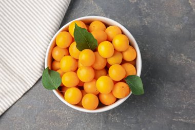 Taze sarı kiraz erikleri ve yapraklar gri masada, üst manzara