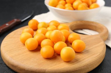 Olgun sarı kiraz erikleri, ahşap tahta ve bıçak siyah masada, yakın plan.