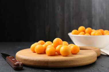 Olgun sarı kiraz erikleri, tahta tahta tahta ve siyah masanın üzerinde bıçak, yakın plan. Metin için boşluk