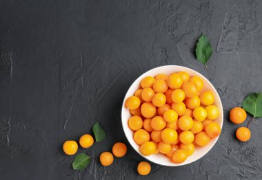 Olgun sarı kiraz erikleri ve siyah masa üzerinde yapraklar, düz yatıyordu. Metin için boşluk