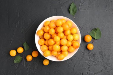 Olgun sarı kiraz erikleri ve yaprakları siyah masanın üzerinde, düz yatıyordu.