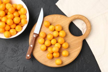 Olgun sarı kiraz erikleri, ahşap tahta ve bıçak siyah masada, düz yatıyordu.