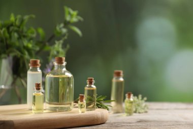 Kapalı alanda, ahşap masa üzerinde gerekli yağlar ve farklı otlar. Metin için boşluk