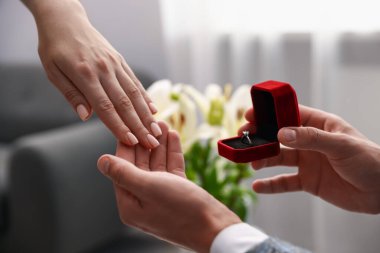 Nişan yüzüklü bir adam içeride kız arkadaşına evlenme teklif ediyor.