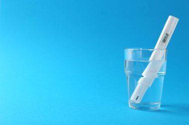 Açık mavi arkaplanda bir bardak suda nitrat testi, metin için boşluk