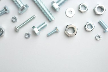 Beyaz arka planda metal cıvatalar ve fındıklar, düz yatış. Metin için boşluk
