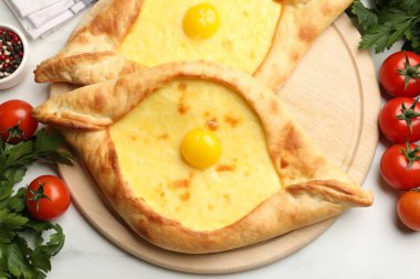Peynirli, yumurtalı, domatesli, maydanozlu ve baharatlı khachapurili beyaz mermer masa, düz.