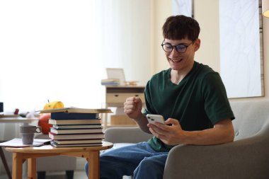 İyi bir sınav sonucunu kutlayan mutlu öğrenci içeride masada.