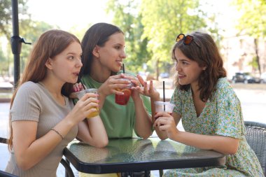 Arkadaşlar açık kafede içeceklerin tadını çıkarıyorlar.