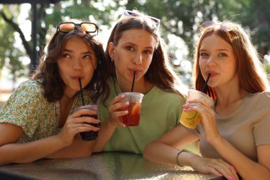 Arkadaşlar açık kafede içeceklerin tadını çıkarıyorlar.