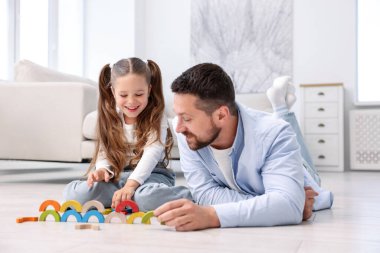 Baba ve kızı evdeki sıcak zeminde oyuncaklarla oynuyorlar. Isıtma sistemi