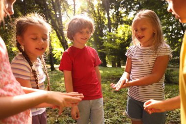 Parkta taş, kağıt ve makas oynayan sevimli çocuklar.
