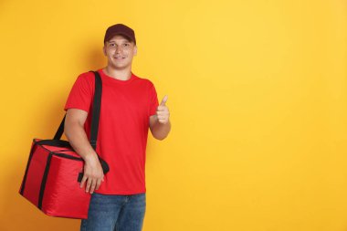 Termal çantalı kurye turuncu arka planda onay gösteriyor, mesaj için yer var. Yemek dağıtım servisi.