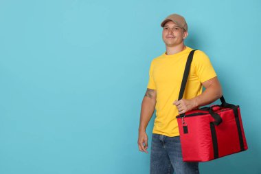 Açık mavi arka planda termo çantalı kurye, mesaj için boşluk. Yemek dağıtım servisi.