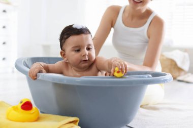 Anne küçük bebeğini evde yıkıyor, yakın plan.