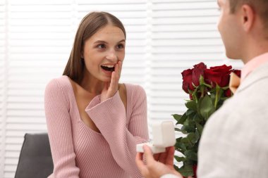 Nişan yüzüğü ve gül buketi olan bir adam duygusal kız arkadaşına evlenme teklif ediyor.