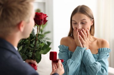 Nişan yüzüğü ve gül buketi olan bir adam mutlu kız arkadaşına evlenme teklif ediyor.