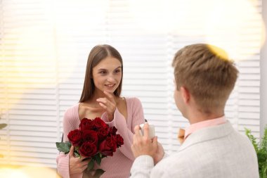 Nişan yüzüğü ve gül buketi olan bir adam mutlu kız arkadaşına evlenme teklif ediyor. Bokeh etkisi