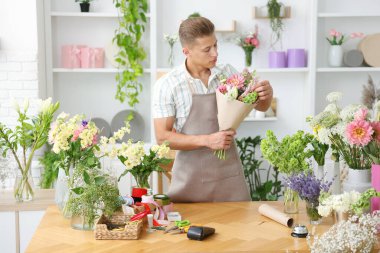 Profesyonel çiçekçi dükkandaki ahşap masada çiçek buketi yapıyor.