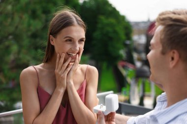 Nişan yüzüklü bir adam dışarıda mutlu kız arkadaşına evlenme teklif ediyor.