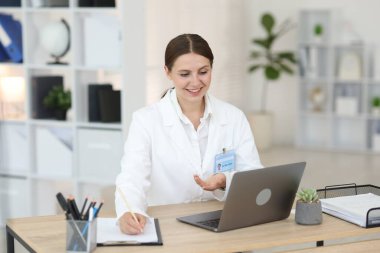 Teletıp. Doktor içeride bilgisayarla hastayla görüntülü konuşma yaparken not alıyor.