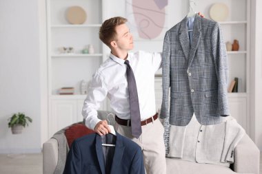 Hazırlanıyor. Genç adam evde kıyafet seçiyor.