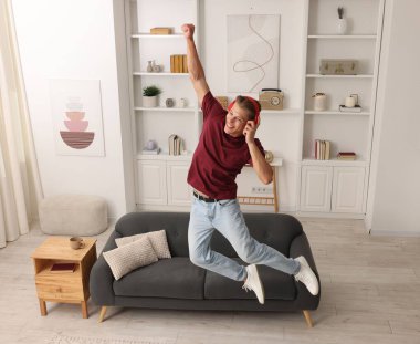 Evde müzik dinlerken zıplayan mutlu bir adam.