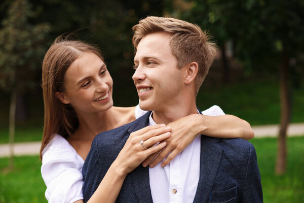 Предложение о браке. Женщина с обручальным кольцом обнимает своего улыбающегося жениха на улице