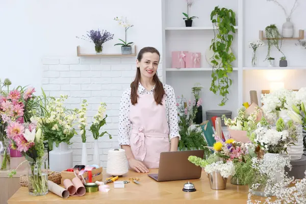 Dükkandaki ahşap masada çalışan profesyonel bir çiçekçi.