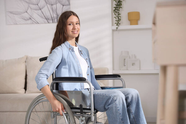 Smiling teenage girl in wheelchair at home