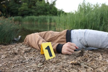 Adli tıp uzmanlığı. Cesedin bulunduğu olay yeri ve gölün yakınındaki işaret, yakın plan.