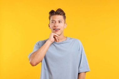 Hayaller gerçek oluyor. Pozitif genç adam sarı arka planda bir şeyler düşünüyor.