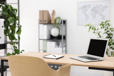 Ofisteki ahşap masada dizüstü bilgisayarı ve kırtasiyesi olan şık bir iş yeri.