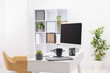 Ofisteki beyaz masa üzerinde modern bilgisayar, dizüstü bilgisayar ve kırtasiye ile şık bir iş yeri