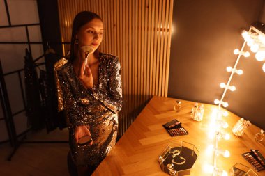 Tuvalet masasında hazırlanırken makyaj yapan güzel bir kadın.